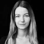 PACE events Schwarz-Weiß-Porträt einer jungen Frau mit langem, glattem Haar und neutralem Gesichtsausdruck, die vor einem schlichten schwarzen Hintergrund direkt in die Kamera schaut.