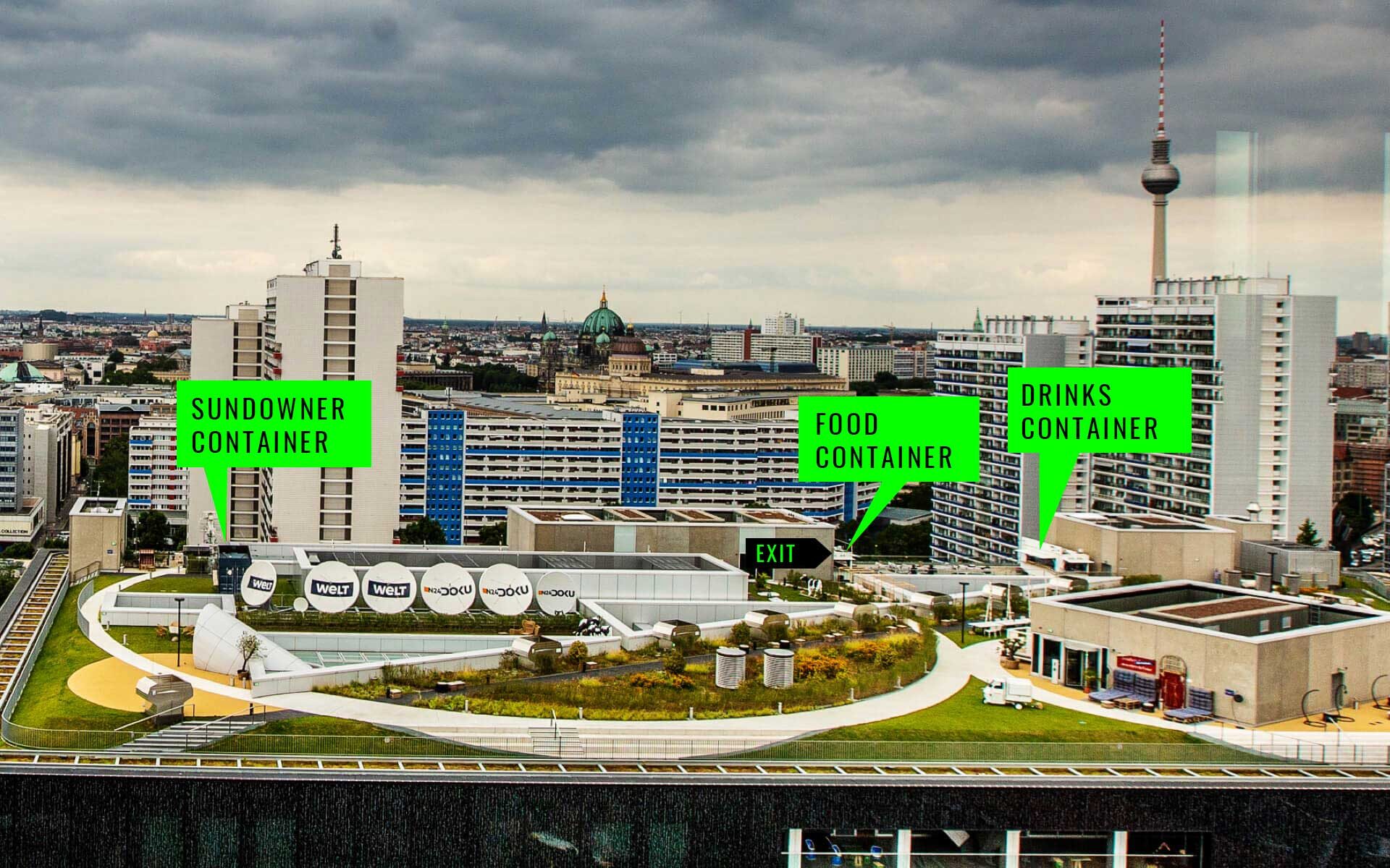 PACE events Ein Dachgarten mit beschrifteten Leuchtreklamen, die auf Dämmerungs-, Essens- und Getränkebehälter hinweisen, vor einer Stadtkulisse mit hohen Gebäuden und einem bewölkten Himmel. Der Berliner Fernsehturm ist im Hintergrund zu sehen.