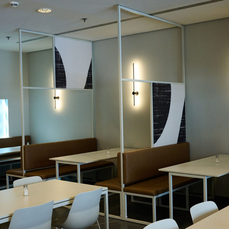 PACE events Moderner Essbereich mit weißen Tischen, braunen gepolsterten Bänken und weißen Stühlen. Minimalistische Wandleuchten und abstrakte Kunsttafeln schmücken den Raum und verleihen ihm ein klares, zeitgemäßes Ambiente.