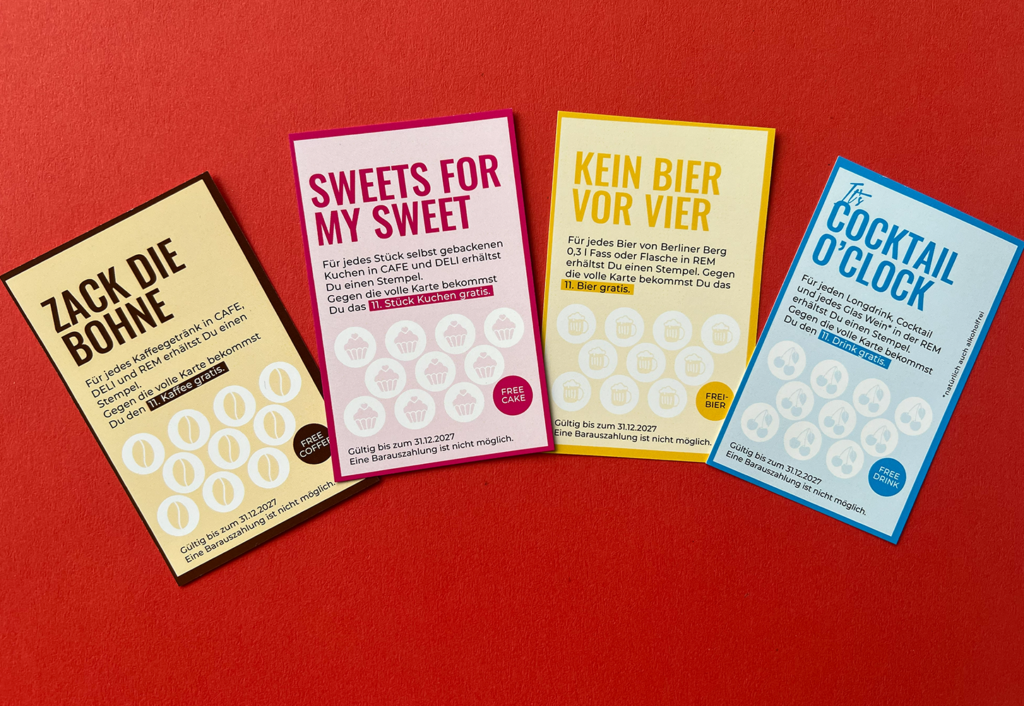 Vier farbenfrohe Couponkarten in deutscher Sprache sind nebeneinander auf rotem Hintergrund angeordnet. Jede Karte bietet verschiedene Angebote für Speisen oder Getränke zum Saisonstart, mit Icons und fetten Überschriften in Schwarz, Pink, Gelb und Blau.