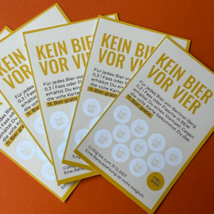 Vier gelbe Bonuskarten mit der Aufschrift „KEIN BIER VOR VIER“ liegen fächerförmig auf einer orangefarbenen Unterlage ausgebreitet. Sammeln Sie Stempel auf diesen Karten, um nach acht Stempeln ein Gratisbier zu erhalten – deutsche Texte und Bierkrug-Symbole verleihen dem Ganzen eine verspielte Note.