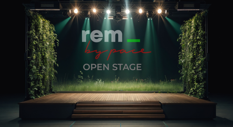 Eine Holzbühne mit Grünpflanzen und Gras, beleuchtet von Scheinwerfern. Im Hintergrund steht in großen Lettern der Schriftzug rem_ by pace OPEN STAGE und lädt verborgene Talente ein, im Scheinwerferlicht zu glänzen.