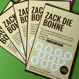 Vier „Bonuskarten für Zack die Bohne“ auf einem grünen Untergrund, jeweils mit Stempelkreisen zum Stempelsammeln. Sammeln Sie zehn Stempel und genießen Sie einen kostenlosen Kaffee. Der Text ist auf Deutsch.